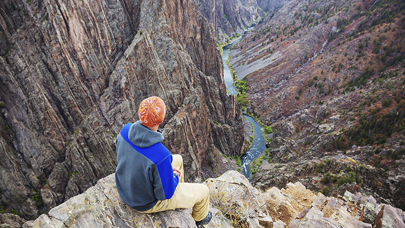 Hiker looking down at Black Canyon of Gunnison on the San Juan Skyway route