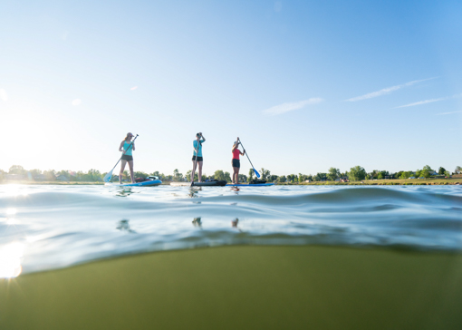 Three women paddle boarding at Lake Elmo State Park