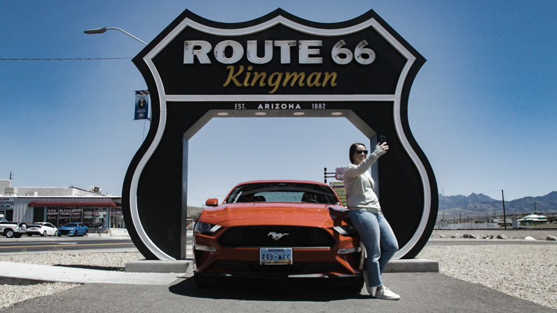 Woman taking a selfie with car in front of Route 66 sign