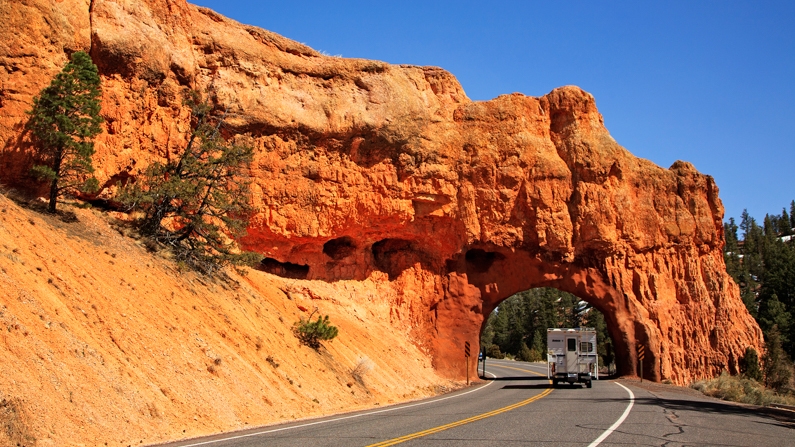 Camper driving through arch in Red Canyon , Utah on Highway 12 